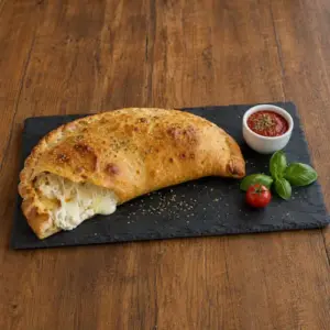 Three cheese calzones filled with ricotta, mozzarella and Parmesan beside warm tomato sauce