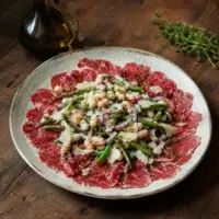 Thin beef carpaccio with green beans, cannellini beans, red onion, Parmesan and thyme dressing.