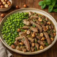 Air Fryer Mint Lamb Hazelnuts served on a rustic wooden table with peas and toasted hazelnuts