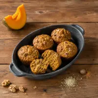 Homemade pumpkin muffins with walnuts, pumpkin spice and almond flour on a rustic wooden table.