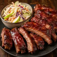 air fryer BBQ spare ribs served on a rustic wooden table with coleslaw and smoky glazed pork ribs
