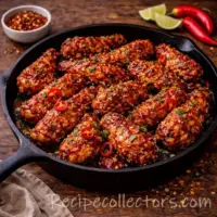 garlic chicken bites seared golden in a skillet on a dark rustic wooden table