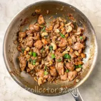 spicy cashew chicken in a skillet on a very dark heavy rustic oak wooden table