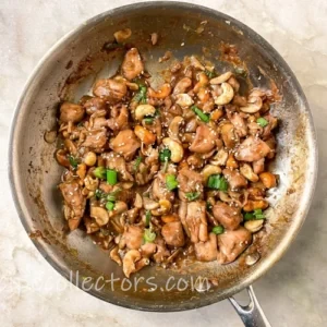 spicy cashew chicken in a skillet on a very dark heavy rustic oak wooden table