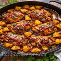 Caramelized Pineapple Glazed Chicken Skillet met gekarameliseerde ananas en sappige kip in een gietijzeren pan op een robuuste houten tafel.